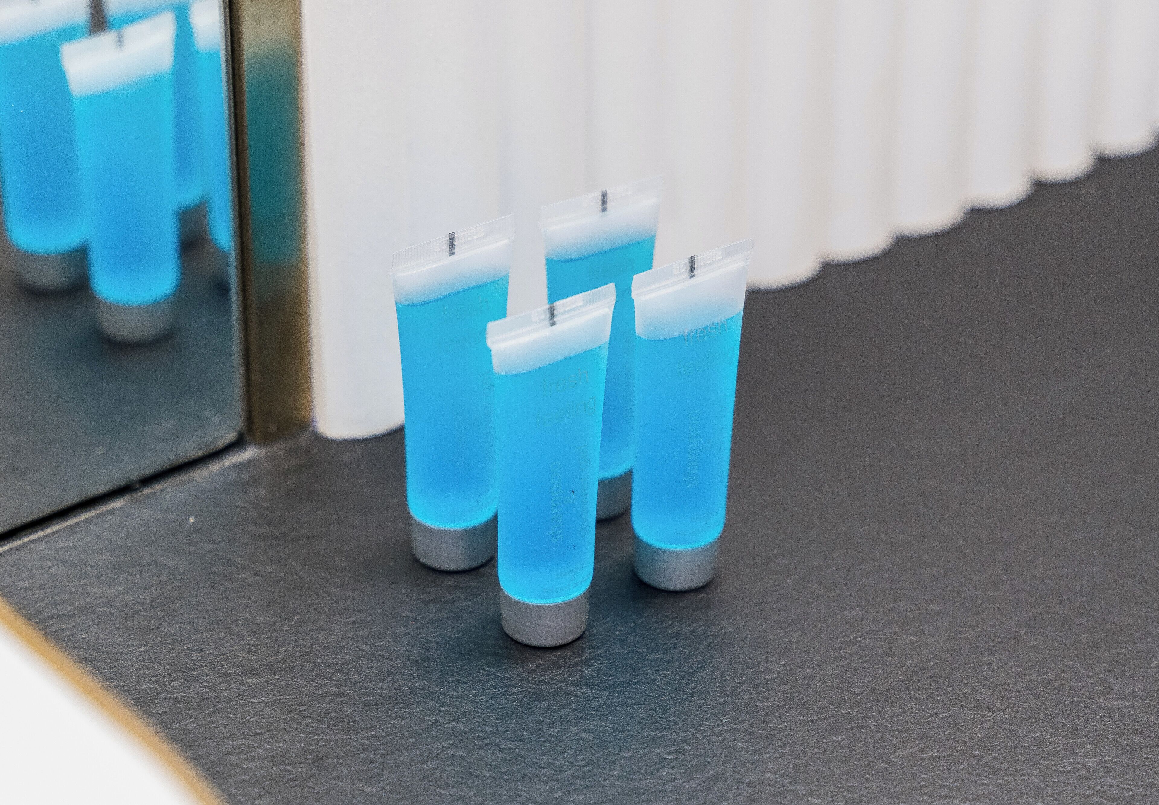 Four blue cylindrical objects with gray bases on a dark surface.