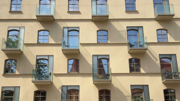 En byggnad med flera våningar, balkonger, rektangulära fönster och en slät fasad.