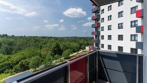 A modern building with balconies overlooking a forested area.