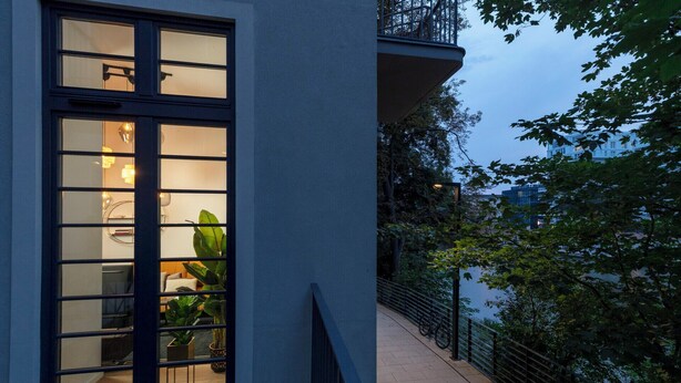 Ein modernes Gebäude mit großen Fenstern, einem Balkon und einem Weg, der zu einem Gewässer führt.