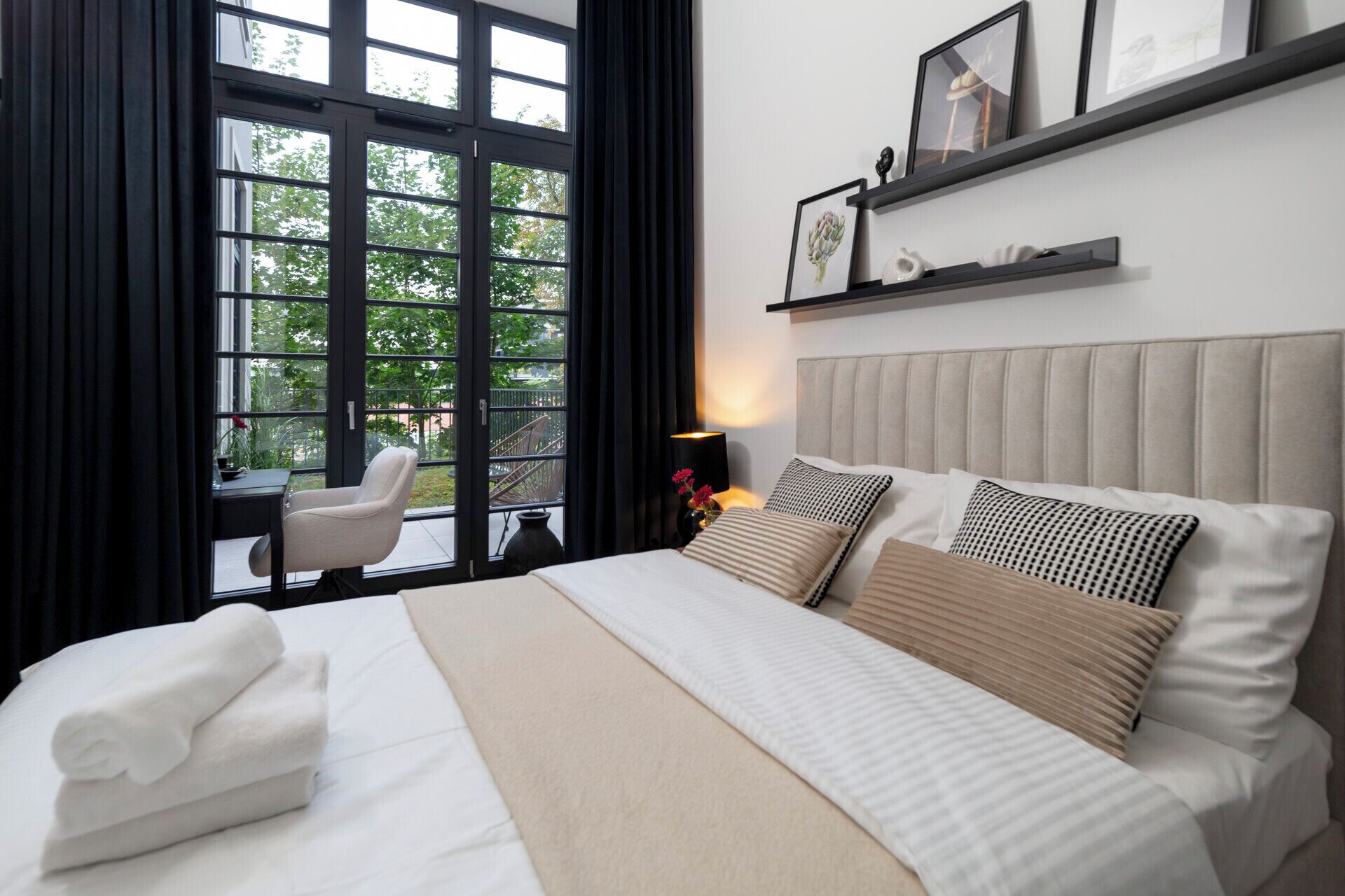 Ein Hotelzimmer mit Bett, Stuhl, Schreibtisch und einem Fenster mit Vorhängen.