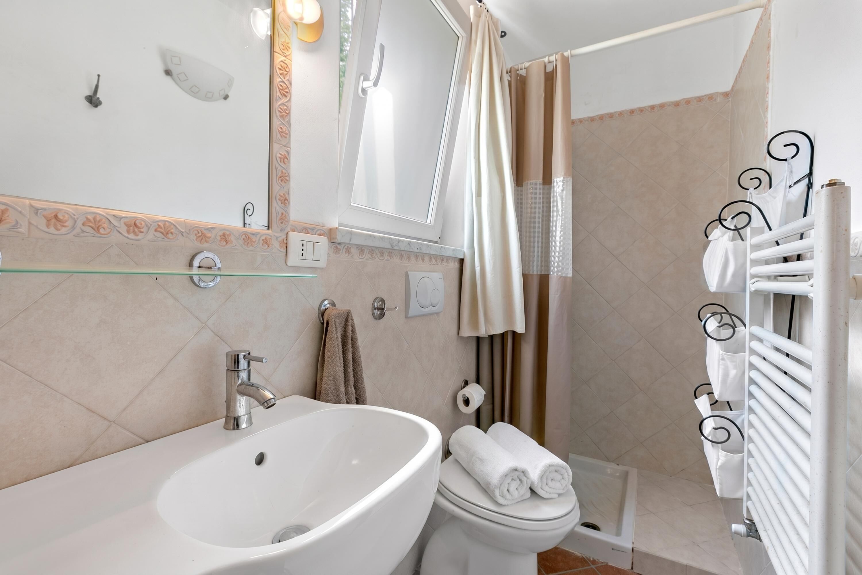 A bathroom with a sink, toilet, shower, and a towel rack.