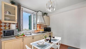 A kitchen with a dining table set for two, a microwave, a stove, and cabinets. - Appartamento Miramare - Amazing View in Versilia, Seravezza, Italy (Seravezza)