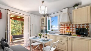 A kitchen with a dining area, a view of the outdoors, and a modern chandelier. - Appartamento Miramare - Amazing View in Versilia, Seravezza, Italy (Seravezza)
