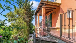 A stone staircase leading to a balcony with a wrought iron railing, surrounded by greenery and a building with a tiled roof. - Appartamento Miramare - Amazing View in Versilia, Seravezza, Italy (Seravezza)