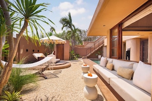 A modern outdoor living area with a hammock, seating, and a pool. - Baia Villas Uluwatu (Pecatu)