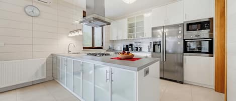 A modern kitchen with a central island, stainless steel appliances, and white cabinetry.