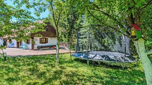 A trampoline in a grassy area with a house in the background. - Grandpa's House With Pool, Gornja Stubica, Croatia (Gornja Stubica)
