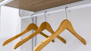 Un armario con perchas de madera y una puerta blanca.