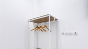 Un armario metálico blanco con tres estantes y una parte superior de madera, frente a una pared blanca con cuatro enchufes.