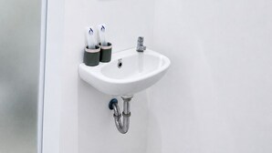 Un baño blanco con lavamanos, espejo y dos porta cepillos de dientes.