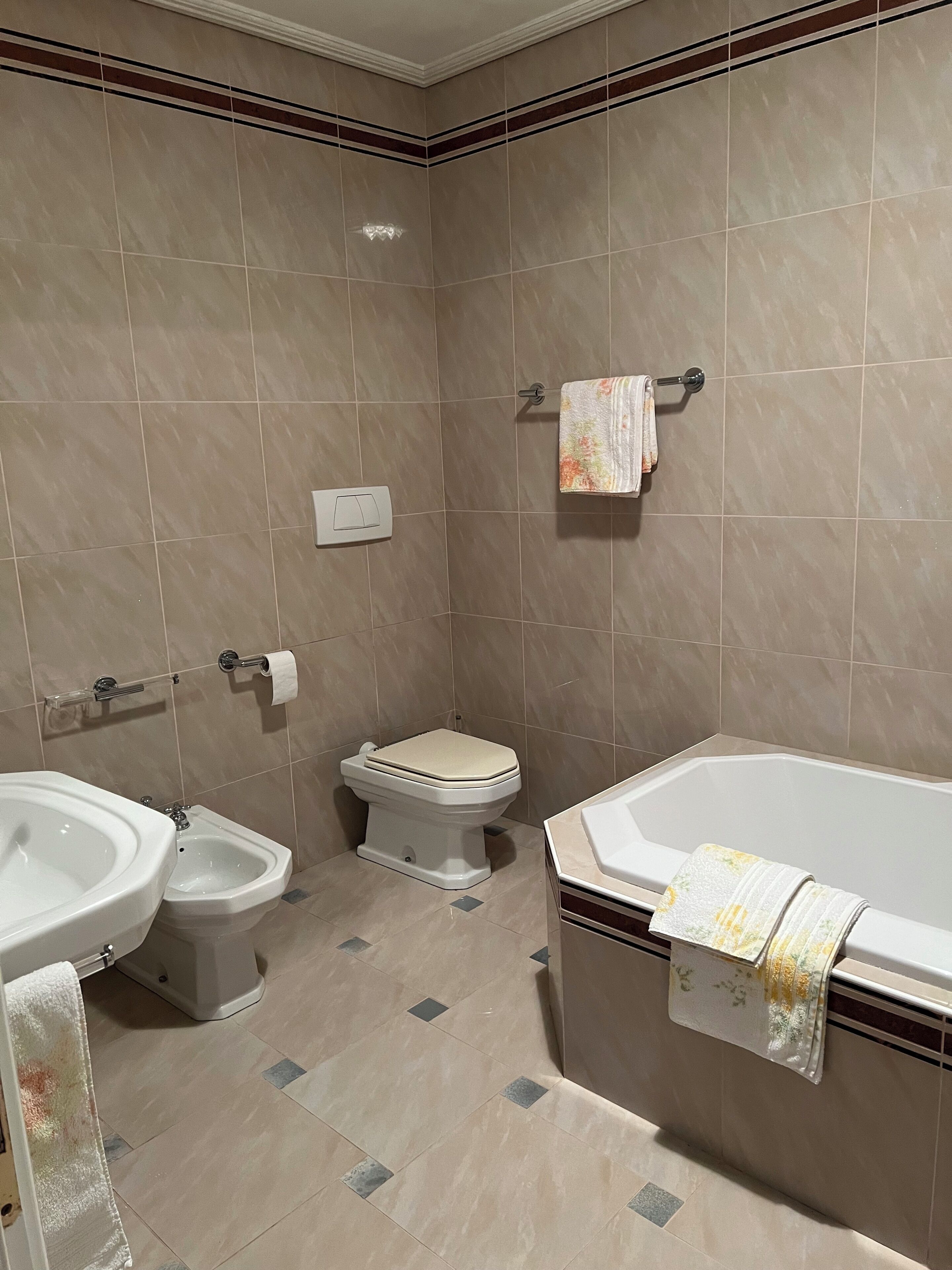 Une salle de bain équipée d’un bidet, de toilettes, d’une baignoire et de deux lavabos.