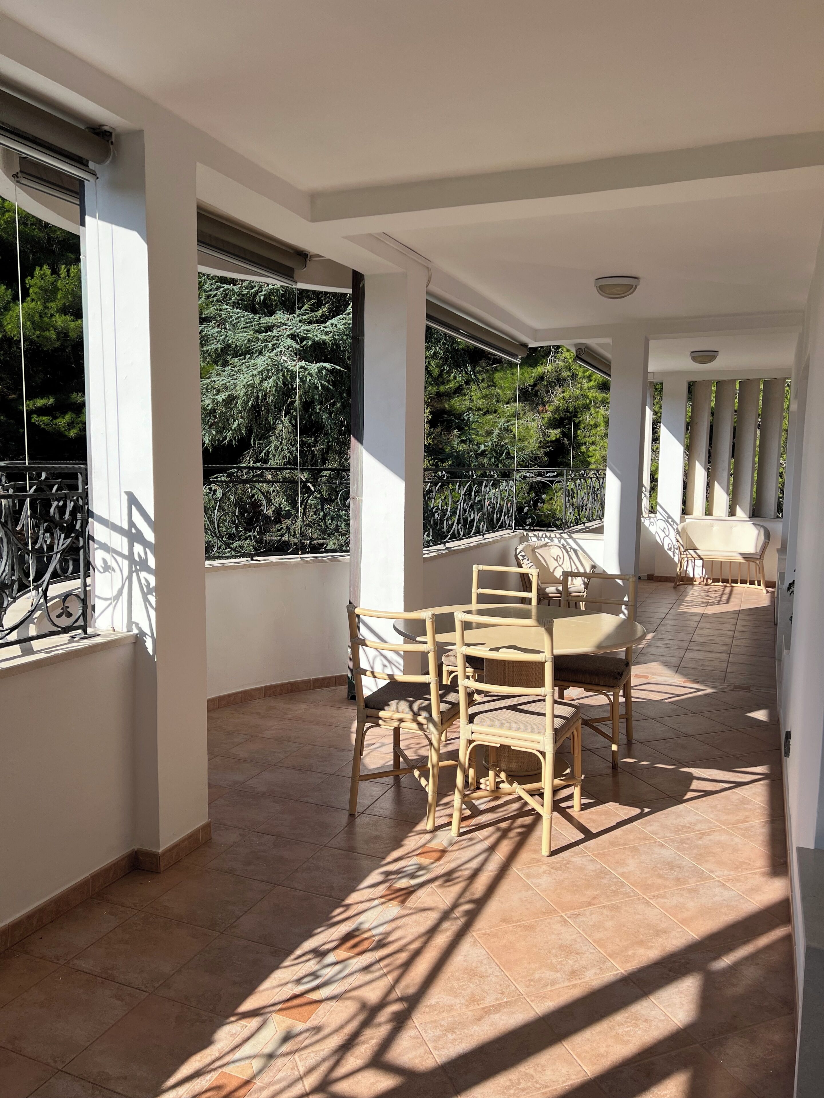 Un patio soleado con una mesa y sillas de comedor, ventanas amplias y vistas a zonas verdes.