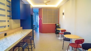 Un interior moderno con una zona de bar, asientos y un ventilador de techo.