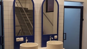 Baño público con dos lavamanos, espejos y una puerta azul.
