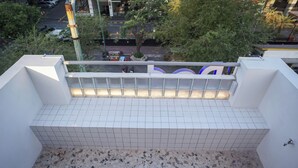 Terraza en la azotea con piso de baldosas, barandilla y vista de la calle.