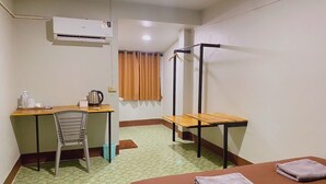 Quarto de hotel com cama, escrivaninha, cadeira, cadeira suspensa e ar condicionado.
