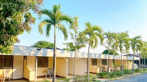 Uma fileira de edifícios térreos, com quartos individuais, cada um com porta e janela.