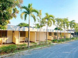 A row of single-story buildings with individual rooms, each with a door and a window.