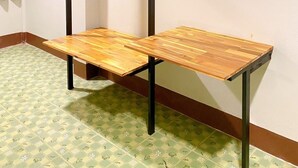 Quarto com mesa de madeira, estrutura de metal preto e chão estampado.