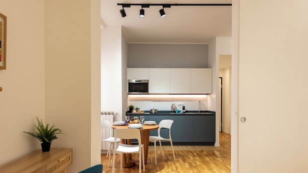 Une cuisine moderne avec un coin repas, un plancher en bois et une plante en pot.