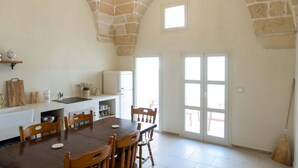 Een ruime keuken met een stenen plafond, een eettafel met stoelen, een inbouwoven en een raam.