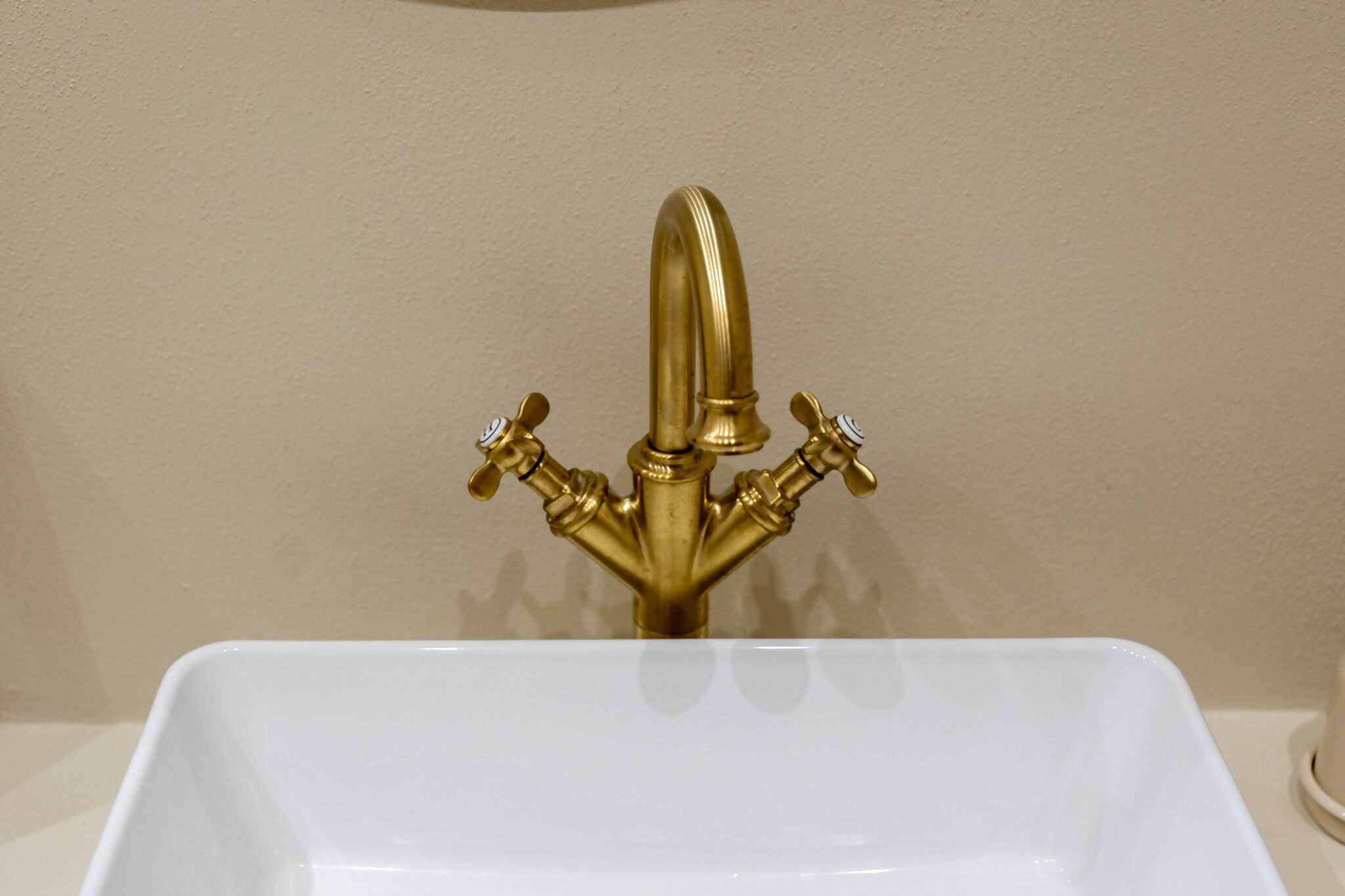 A white sink with a gold faucet.