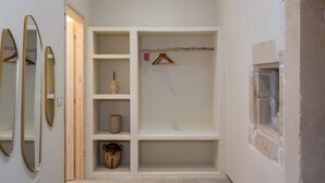 Een kamer met een inbouwkleerkast, een spiegel en een plank met een hangende kledingstuk.