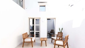 Een klein, afgesloten terras met houten meubels en een tafel, een deur naar een binnenruimte, en een klein raam.