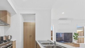 A modern kitchen with a gas stove, stainless steel sink, and wooden cabinets. - Spacious Modern Retreat in Officer | Perfect for Families (Officer)