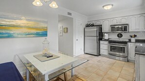 Una cucina moderna con mobili bianchi, elettrodomestici in acciaio inossidabile e un tavolo da pranzo in vetro.