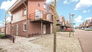 En modern byggnad i två våningar med en fasad av tegel, en balkong och en grusbelagd mark.