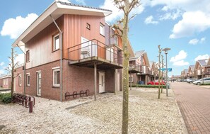 Ein modernes, zweistöckiges Gebäude mit Backsteinfassade, einem Balkon und Kiesgrundstück.