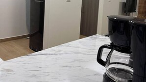 Una cucina moderna con un piano di lavoro in marmo, un frigorifero nero e una macchina per il caffè.