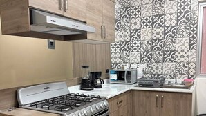 Una cucina moderna con piano cottura a gas, forno, microonde e macchina da caffè.