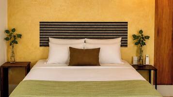 Una cama con cabecera, una mesita de noche con lámpara y un aplique de pared.