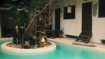 Una piscina interior con una estructura de árbol de madera, sillas de descanso y un columpio colgante.