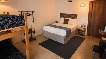 Una cama individual con cabecera, un escritorio con silla, una lámpara colgante y un ventilador de techo.
