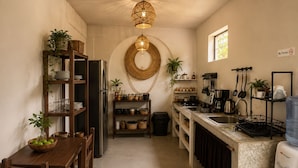 A compact kitchen with a central island, a refrigerator, and various kitchen appliances. - Casa Ceiba  (Puerto Escondido)