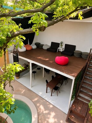 An outdoor patio with seating, a pool, and a staircase.