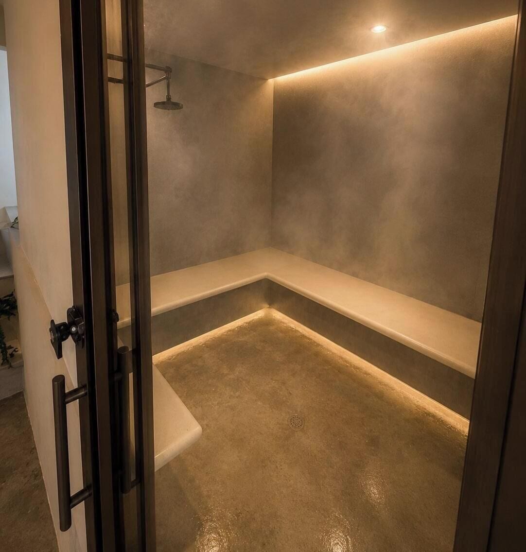 Un baño moderno con puerta de vidrio, ducha y banco.