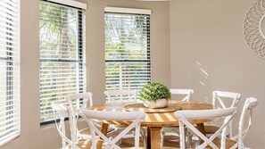 A dining area with a round wooden table, white chairs, and a potted plant. - The Sails 1/21 Beech Street  Evans Head (Evans Head)