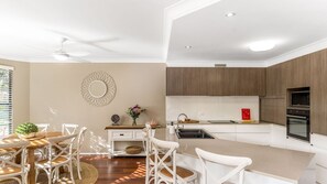 A modern kitchen with a central island, white cabinetry, and a built-in oven. - The Sails 1/21 Beech Street  Evans Head (Evans Head)