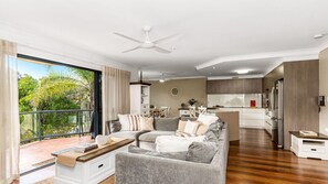 A modern living room with a grey sofa, a coffee table, and a balcony with a view of greenery. - The Sails 1/21 Beech Street  Evans Head (Evans Head)