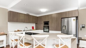 A modern kitchen with a central island, stainless steel appliances, and white cabinetry. - The Sails 1/21 Beech Street  Evans Head (Evans Head)