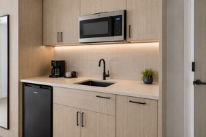 Een moderne keuken met een ingebouwde magnetron, koffiezetapparaat, spoelbak en vaatwasser.