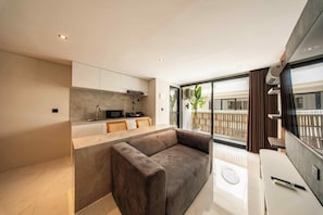 A modern living space with a sofa, a kitchen area, and a balcony with a view. - Salt Lofts Pererenan (Bali)