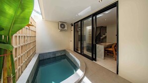En moderne indendørs swimmingpool med et glasværn, et træhegn og en trappe, der fører op til et højere niveau.