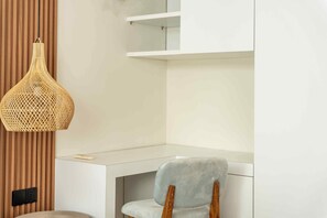A modern room with a desk, a chair, a woven light fixture, and a built-in shelf. - Salt Lofts Pererenan (Bali)