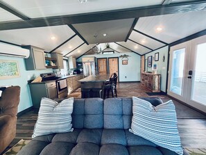 A spacious living area with a sofa, striped pillows, a kitchen with a central island, and a dining area.